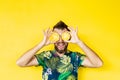 Young bearded man holding slices of pineapple in front of his eyes, laughing out loud Royalty Free Stock Photo