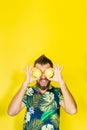 Young bearded man holding slices of pineapple in front of his eyes, laughing out loud Royalty Free Stock Photo