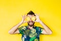 Young bearded man holding slices of pineapple in front of his eyes, laughing