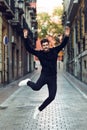 Young bearded man jumping in urban background with open arms wea Royalty Free Stock Photo