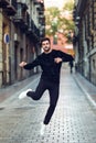 Young bearded man jumping in urban background with open arms wearing casual clothes. Royalty Free Stock Photo