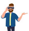 Young bearded man looking through binoculars. Person holding binocular and pointing or presenting hand to copy space. Royalty Free Stock Photo