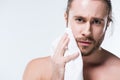 Young bearded man looking to camera while holding bath towel in hand close to his cheek, Royalty Free Stock Photo