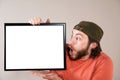 Young bearded man making funny face, holding a blank sign board. Studio shot on gray Royalty Free Stock Photo