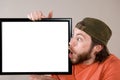 Young bearded man making funny face, holding a blank sign board. Studio shot on gray Royalty Free Stock Photo