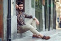 Young bearded man, model of fashion, sitting in an urban step we