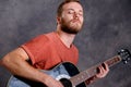 Young bearded man playing acoustic guitar