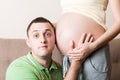 Young bearded man putting his ear close to his pregnant wifes abdomen and Listening it Royalty Free Stock Photo