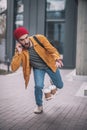 Young bearded man in a red hat talking on the phone and dropping the coffee cups