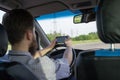 Young bearded man sitting behind the wheel and looking for route by navigation map in smartphone. Rear view Royalty Free Stock Photo