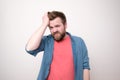 Young bearded man suffers from severe headache or is under stress, he holds forehead with hand and looks at the camera. Royalty Free Stock Photo