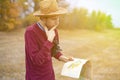 Young bearded man in summer hat lost in the forest and search the road on map f