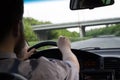 Young bearded man in summer shirt driving a car on highway. Both hands holding a steering wheel Royalty Free Stock Photo