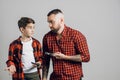 Young bearded man teaching his brother to work with a hammer and pliers