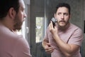 Young bearded man trimming his beard with electric shaver. Royalty Free Stock Photo