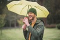 Young bearded man under yellow umbrella having coffee Royalty Free Stock Photo