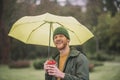 Young bearded man under yellow umbrella having coffee Royalty Free Stock Photo
