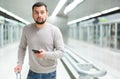 Young man using smartphone to check schedule on subway station Royalty Free Stock Photo