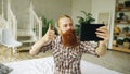 Young bearded man using tablet computer having video chat sitting in bed at home Royalty Free Stock Photo