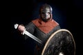 Young bearded man in a Viking-era helmet covering his face holding a sword and shield Royalty Free Stock Photo