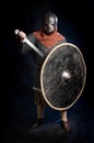 Young bearded man in a Viking-era helmet standind and holding a sword and shield Royalty Free Stock Photo