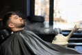 Young bearded man visiting barbershop. Professional shaving service Royalty Free Stock Photo