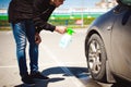 young bearded man washes his car`s wheel rims, spraying water from spray