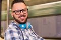 Man wearing plaid shirt and glasses taking public transport underground area. Concept of commute, mobility, city life.