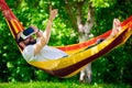 Young bearded man wearing virtual reality goggles relaxing in a garden hammock. Lifestyle VR fun and relax Royalty Free Stock Photo