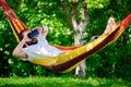 Young bearded man wearing virtual reality goggles relaxing in a garden hammock. Lifestyle VR fun and relax Royalty Free Stock Photo