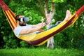 Young bearded man wearing virtual reality goggles relaxing in a garden hammock. Lifestyle VR fun Royalty Free Stock Photo