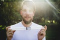 Young bearded man in white clothes holding white Promark 2B drum sticks in his hand