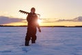 winter fishing. Young man fisherman with a drill for ice fishing. sunrise Royalty Free Stock Photo