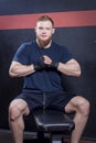 Bearded guy, a mixed martial arts fighter, sits on a couch, brought his hands together in front of his chest. Looks at the camera. Royalty Free Stock Photo