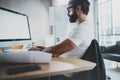 Young bearded professional architect wearing eye glasses working at modern loft studio-office with desktop computer