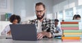 Young bearded sitting at desk and using laptop in classroom