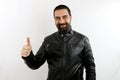 Young bearded smiling biker man with leather jacket on isolated white background making thumb up right sign.