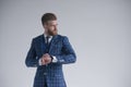 Young bearded stylish businessman leader indoors wearing three-piece suit with watch looking aside serious. isolated on grey. Royalty Free Stock Photo