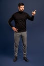Young bearded stylish teacher or business man pointing finger side. Full body length portrait isolated on Pacific Blue studio Royalty Free Stock Photo