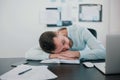 Young bearded tired man sleeping on office table after hard working day in his modern office, work routine concept Royalty Free Stock Photo