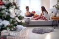 Young beardy guy surprising his girlfriend with Christmas present while having breakfast in bed together