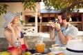 Young beardy male taking photo of attractive blonde with old photo camera