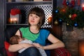 Portrait of young beatuful mother breastfeeding her baby near fireplace on Christmas Eve Royalty Free Stock Photo