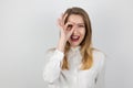 Young beatuiful blond woman holding her hand like magnifying glass near her eye looks surprised, splash of emotions