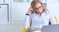 Young beauiful Caucasian businesswoman in glasses working on notebook computer and business document at office.