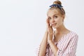 Young and beautful. Portrait of tender and gentle good-looking blond woman in striped pink blouse and headband, touching