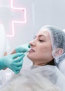 The young beautician doctor preparing to making injection in female lips. The doctor cosmetologist makes lip augmentation Royalty Free Stock Photo