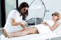 Young beautician removing legs hair with a laser to her client in the beauty salon.