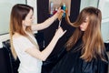 Young beautician trimming or cutting split damaged ends of client s long hair in beauty parlor Royalty Free Stock Photo