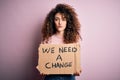 Young beautiful activist woman with curly hair and piercing protesting asking for a change with a confident expression on smart